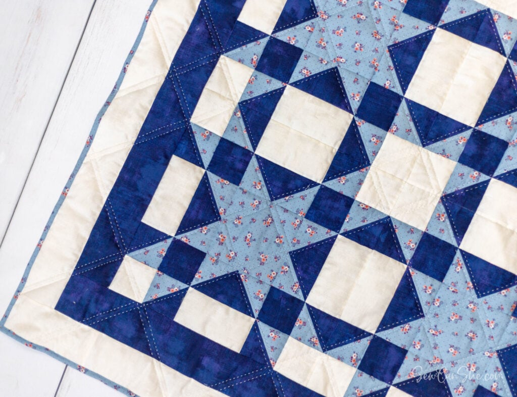 Blue, white, and floral quilt with Amish Star quilt block designs.