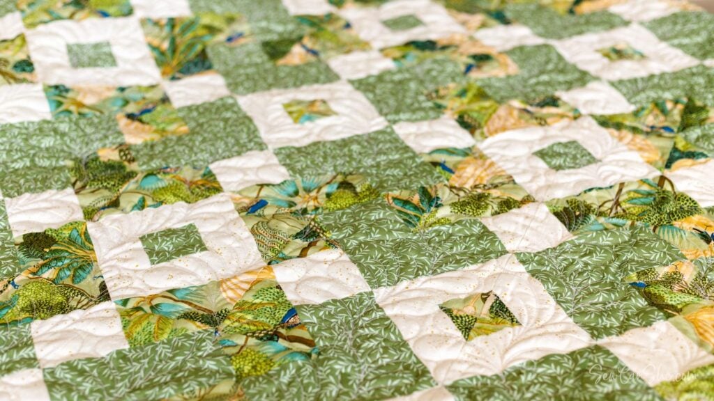 green and cream colored quilt with the classic card trick quilt block design