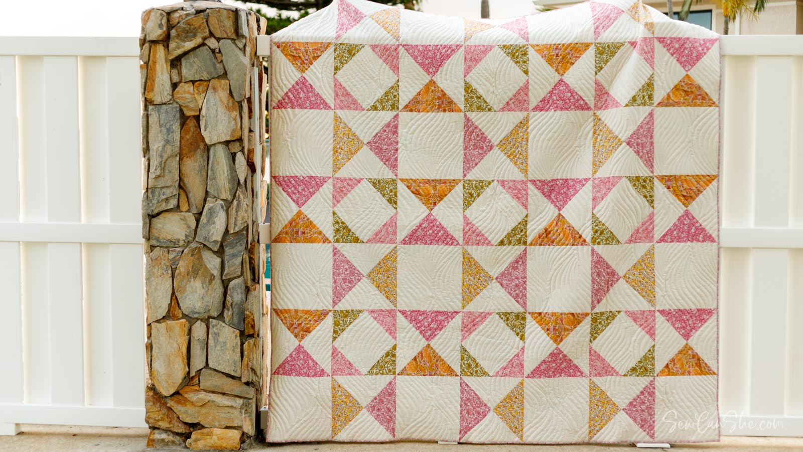 Colorful quilt against a stone wall