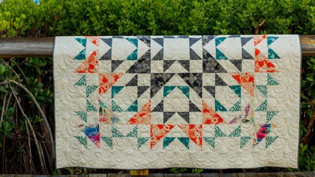 Colorful half square triangle quilt hanging outdoors