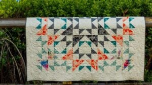 Colorful half square triangle quilt hanging outdoors