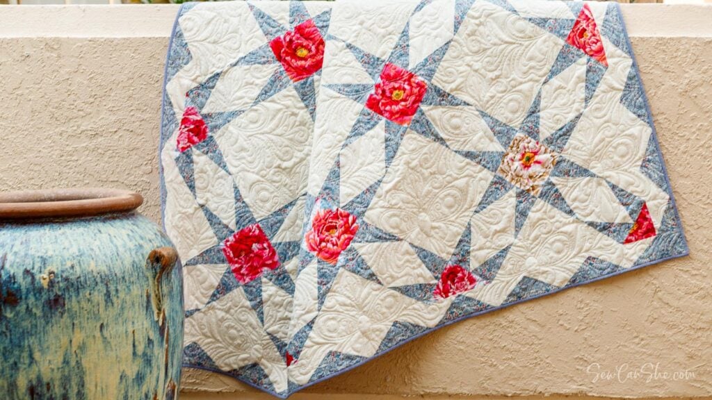 White, blue, and floral red star quilt draped over a wall