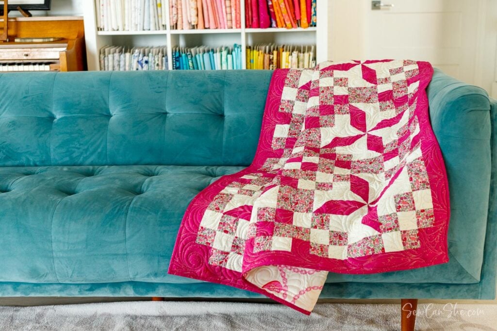 Colorful quilt draped on teal couch