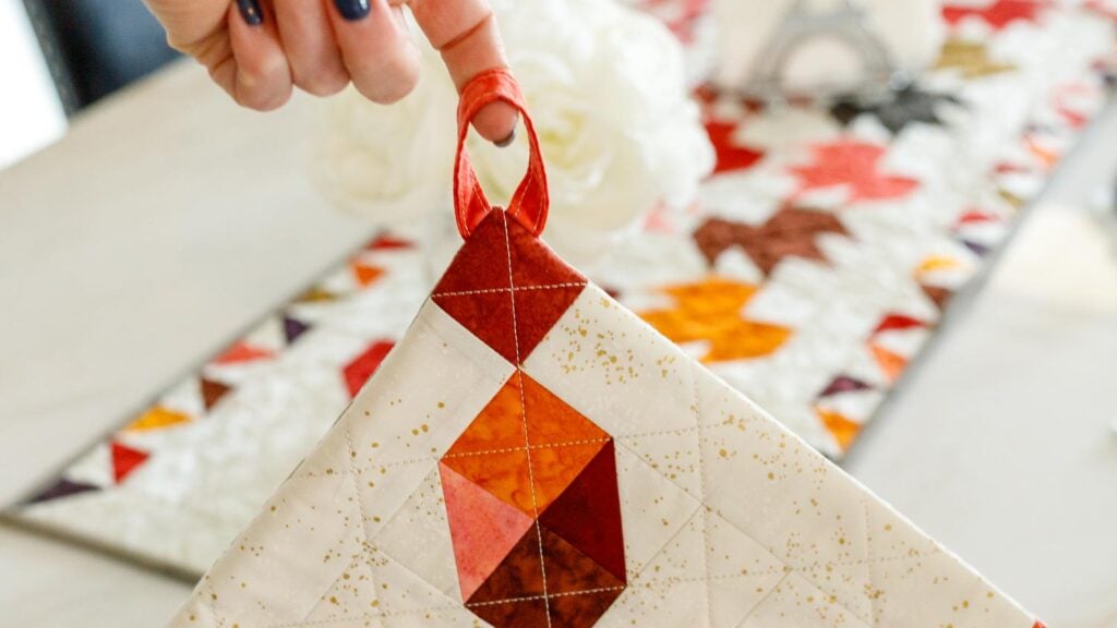 Hand holding a colorful quilted potholder