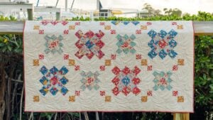 granny square quilt hanging on fence