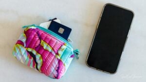 Colorful floral quilted & handmade wallet with cards inside on a white table next to a smartphone.