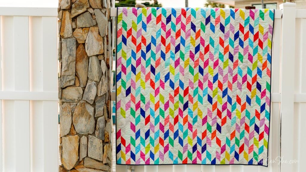Colorful jelly roll fabric quilt hanging on fence