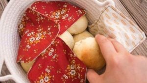 Warm bread rolls in a basket covered by a homemade roll warmer