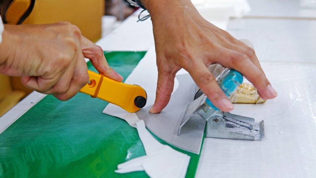 Close-up female hands cutting fabric with patchwork rotary cutter