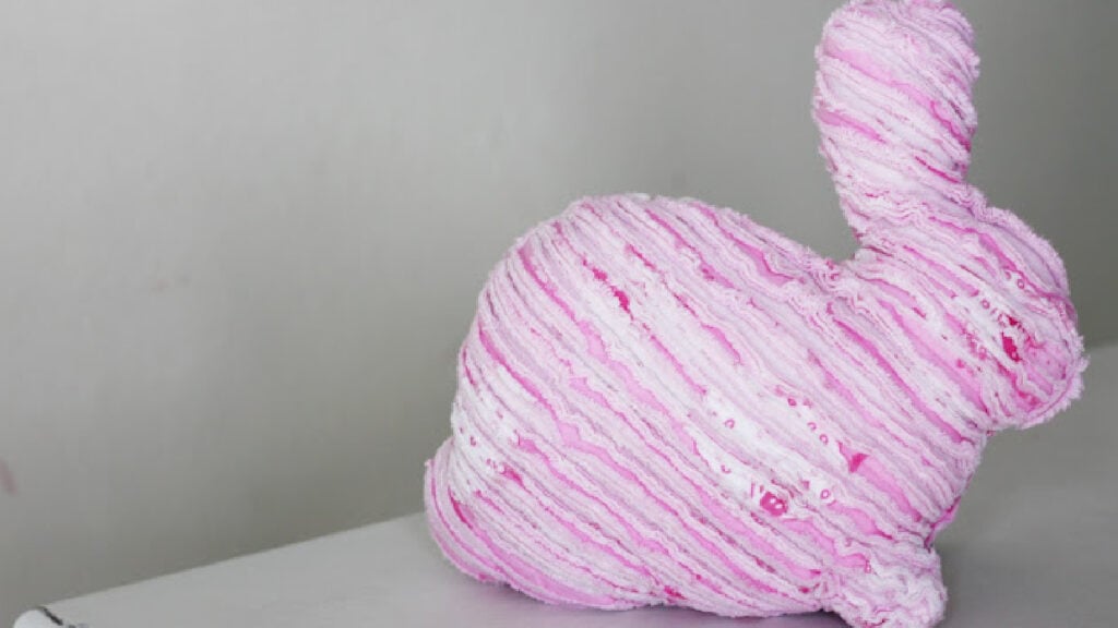 Soft, textured chenille fabric bunny softie with a ribbon bow, used as a handmade gift or Easter mantle decor.