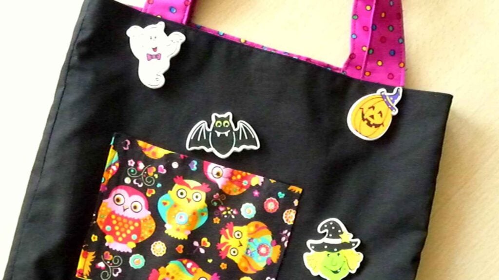 simple black tote bag with pink handles and a pocket, decorated with Halloween figures.