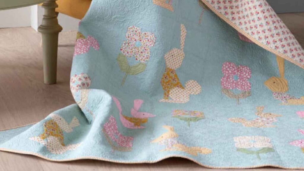 A delicate and nostalgic quilt featuring rows of sweet, pieced hares and stylized flower blocks. Set against a soft sage chambray background, the mix of pastel ginghams and tiny florals creates a "Creating Memories" heirloom look that is both whimsical and sophisticated