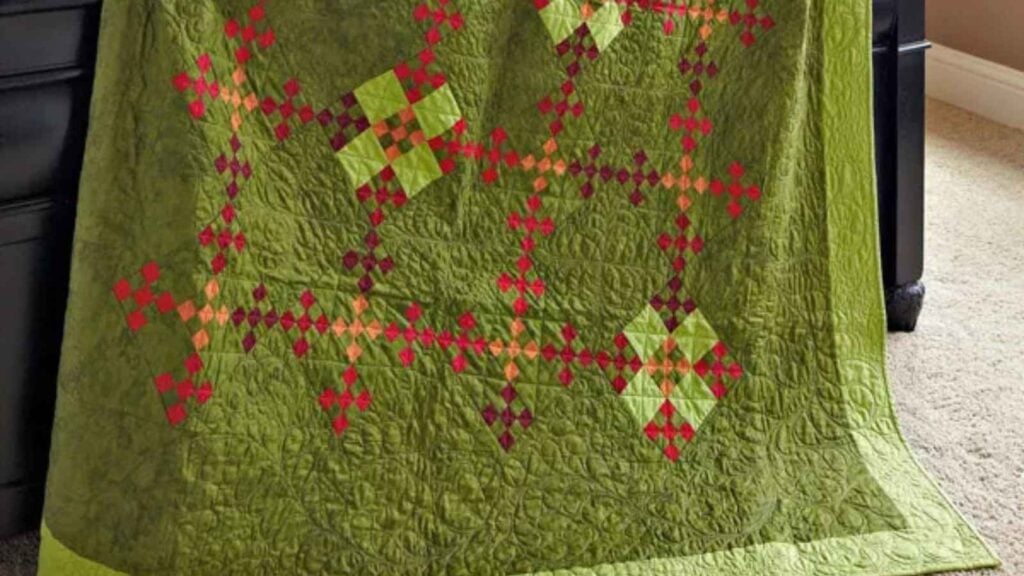 Mossy green quilt with nine patches in warm colors.