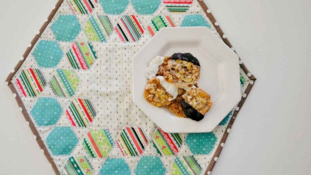 Hexagon table topper sewn with several colorful snowballed quilt units to put on your Christmas table