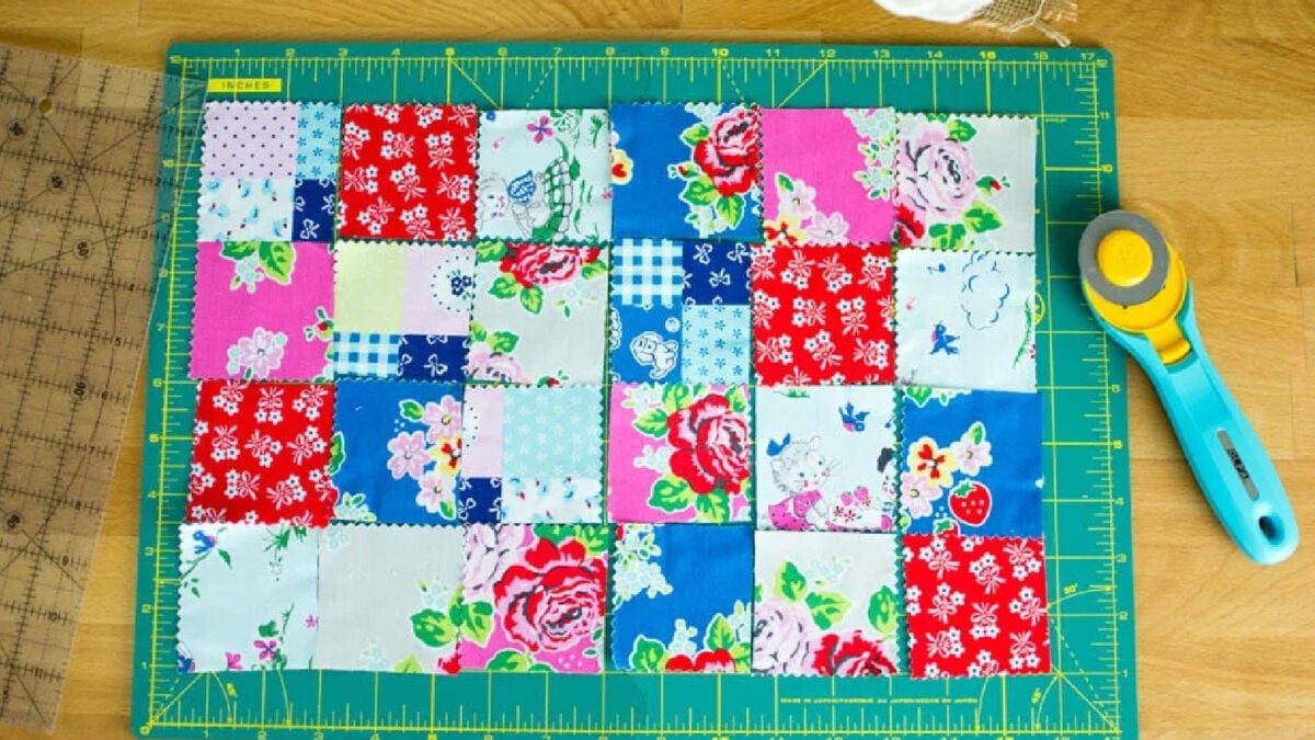Beginner sewing notions including a green cutting mat, rotary cutter, and fabric on a work surface.