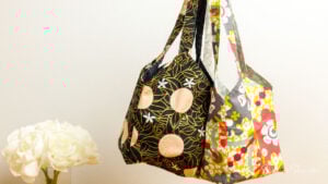 Two handmade Japanese-style square tote bags in modern prints hanging together, showcasing a free 1-yard bag sewing pattern for beginners.