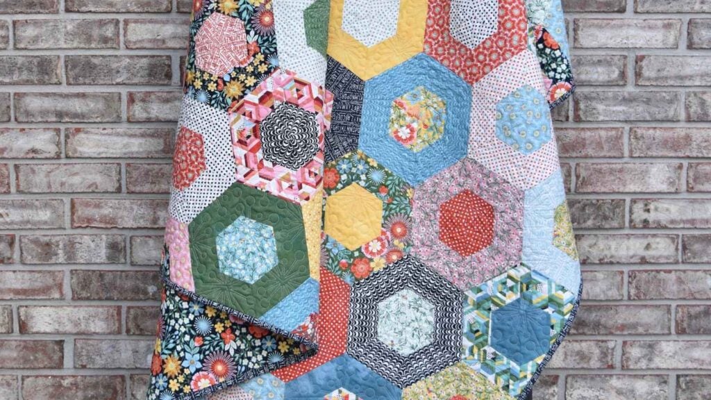 A colorful scrappy strip quilt sewn with dual-tone hexagons.