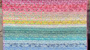 Rainbow-colored Liberty Tana Lawn fabric strip quilt with a sunset-inspired gradient. Each 2.5" fabric strip has a floral design.
