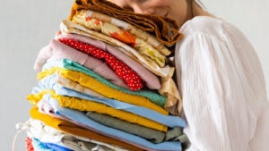 A happy woman holding a pile of fabrics
