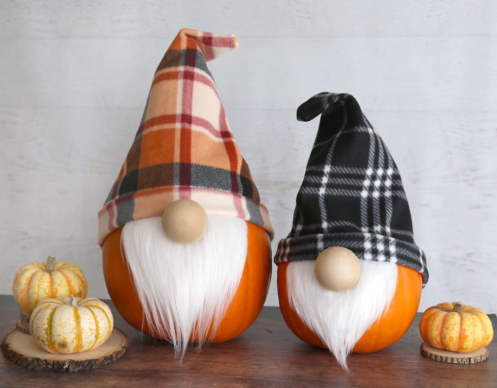 A seasonal pumpkin display with two larger pumpkins dressed up like gnomes