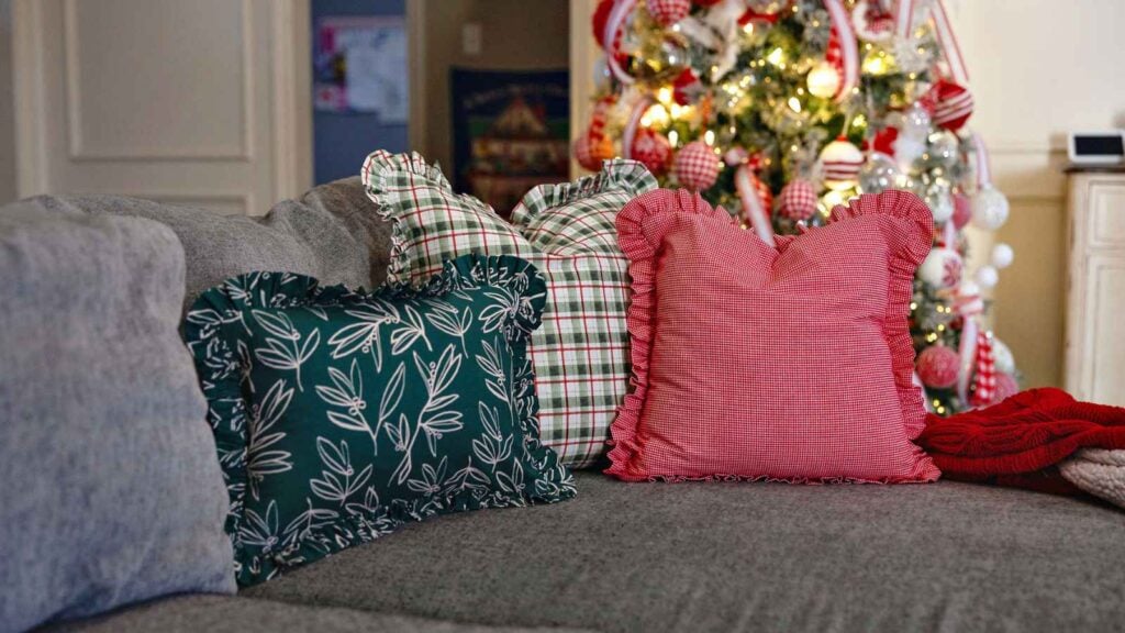 A plush, square accent pillow featuring a wide, gathered fabric ruffle around the entire perimeter, shown in a bright, vintage-style floral print.