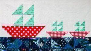 White half square triangle quilt with big and small sailboat quilt blocks to show a free half square triangle quilt pattern
