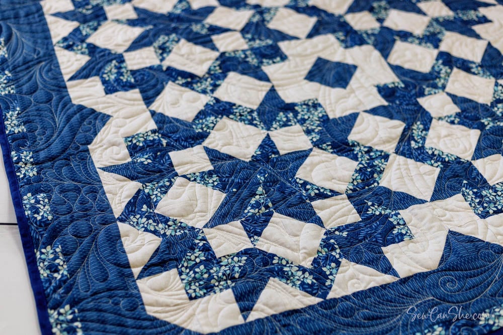Blue, white, and floral quilt with carpenters star designs.