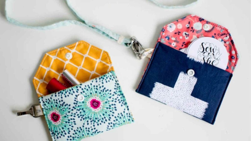 Small handmade fabric wallets in various patterns secured with colorful round plastic snaps.