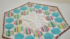 Table runner patterns Handmade Easter egg crumb catcher table topper with pastel hexagon patchwork and decorative quilting.