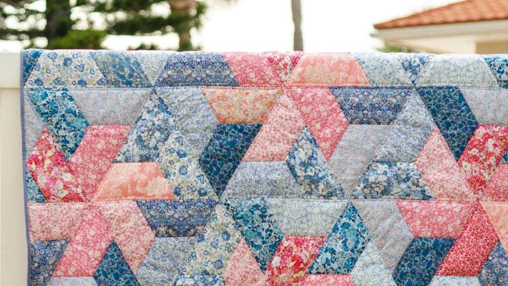pink and blue geometric quilt hanging on a fence