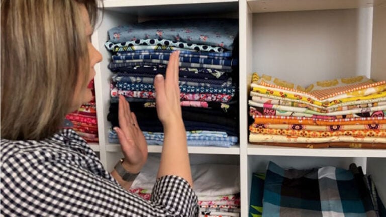 Caroline showing fabric neatly folded on shelves to organize fabric.