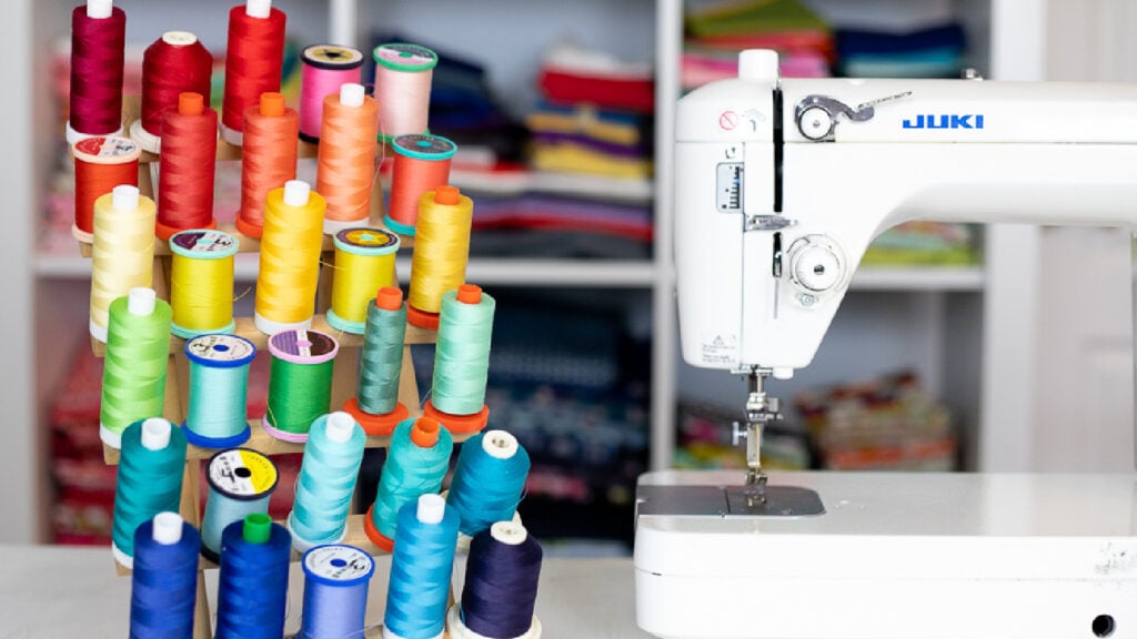 Several spools of colorful Gutermann polyester sewing thread next to a Juki sewing machine.