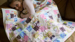 Colorful quilt draped over a child for a fun hobby