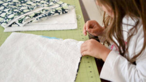 young girl sewing reusable unpaper towels to be environmentally friendly. A perfect beginner friendly spring cleaning project.