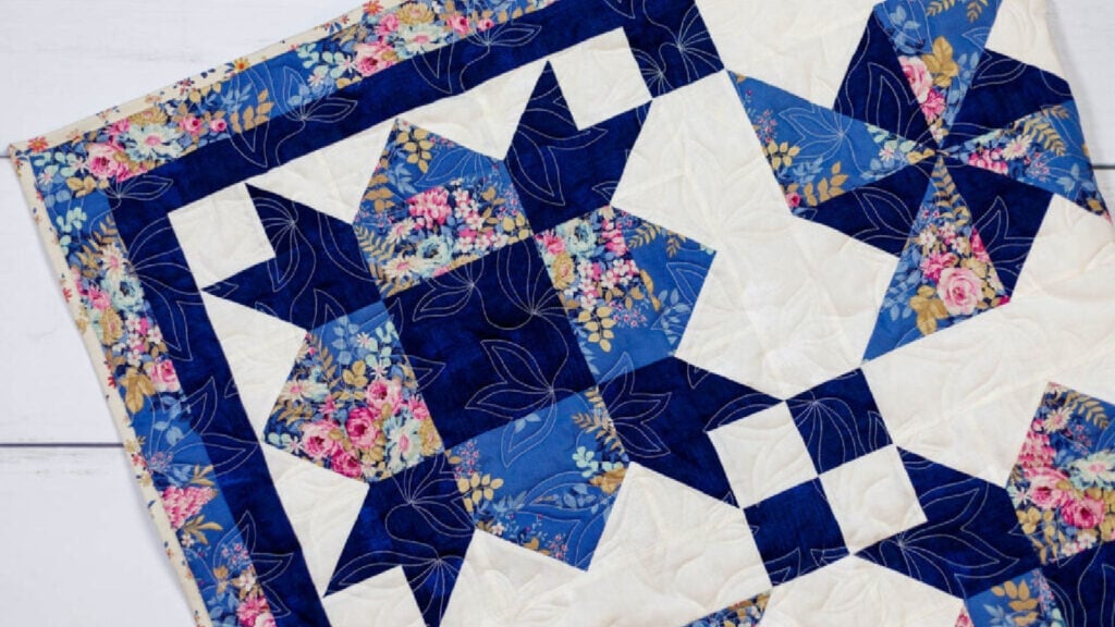 Blue, floral, and white quilt with windmill blocks.