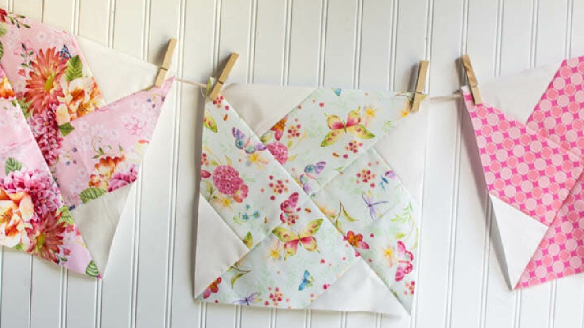 three colorful pink whirlwind quilt blocks hanging on a line.