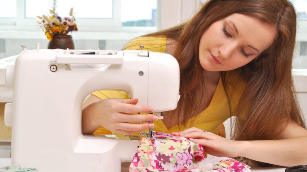 Woman sewing colorful fabric with machine.